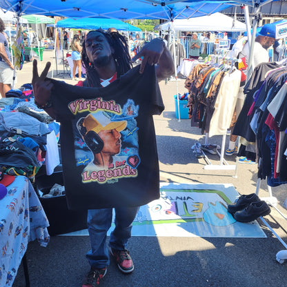 Person holding black Virginia Is for Legends Y2k P tee with colorful graphic at outdoor market